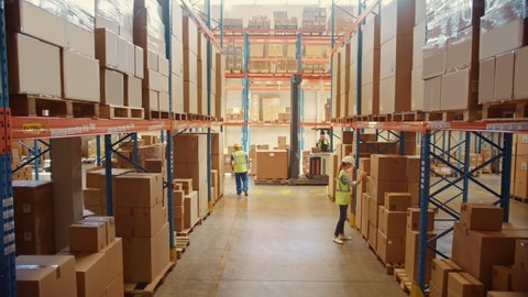 Retail Warehouse full of High Shelves with Goods in Cardboard Boxes has Team of Professionals Scan and Sort Packages, Operate Hand Pallet Trucks and Forklifts. e-Commerce Products Distribution Center