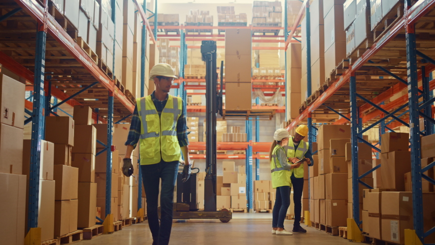 Retail Warehouse full of Shelves with Goods in Cardboard Boxes, Male and Female Supervisors Use Digital Tablet Discuss Product Delivery while Scanning Packages.Forklift Working in Logistics Storehouse Royalty-Free Stock Footage #1059312635