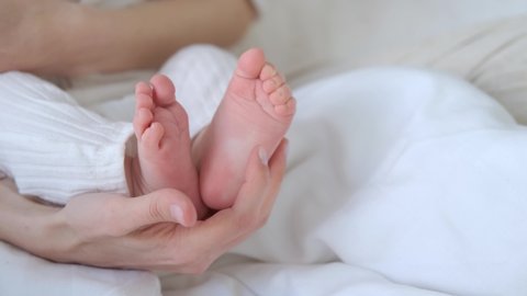close-up woman tickles baby's feet