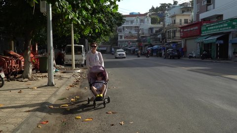 NhaTrang, Vietnam, November,10-2018. A woman with a baby carriage goes along the road.