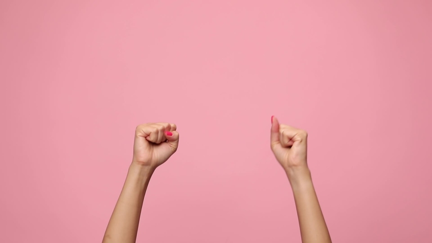 Woman holding fists in the air, moving and dancing, celebrating victory on pink background | Shutterstock HD Video #1059324434