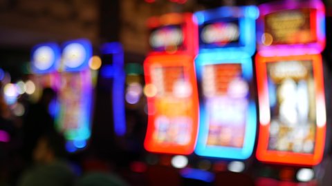Defocused slot machines glow in casino on fabulous Las Vegas Strip, USA. Blurred gambling jackpot slots in hotel near Fremont street. Illuminated neon fruit machine for risk money playing and betting.