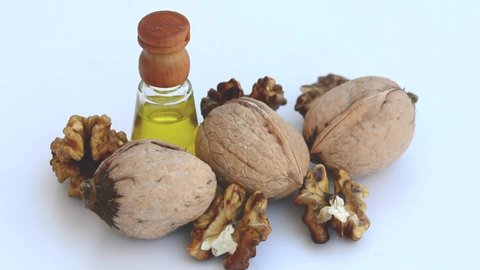 Walnuts, shelled walnuts and a bottle of walnut oil on a rotating white plate