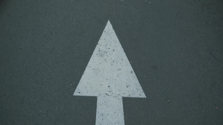 Indonesian white arrow road sign on an asphalt road.