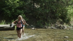 Approaching teenage girls hiking across forest stream / Tibble Fork, Utah, United States