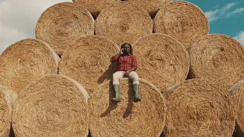 African black farmer sitting on the haystack and having a phone call. High quality 4k footage