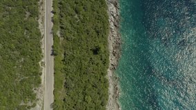 Aerial view Montenegro. Drone video parallel to the Adriatic Sea, rocks and a road in the mountains where you can see cars, trees and water.