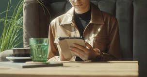 Woman working on tablet, sitting in cafe with coffee cup. Girl in glasses in pause, after work. Online chat with friends, long distance communication. Staying connected. 4K video Slow motion.
