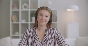 active and positive woman is talking to camera by headphones, portrait of female blogger and webinar host