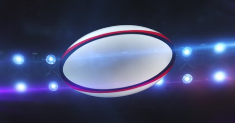 Flying rugby ball with flashing stadium spotlights in the night. Rotating sport ball. Sport 4k video background in endless loop.