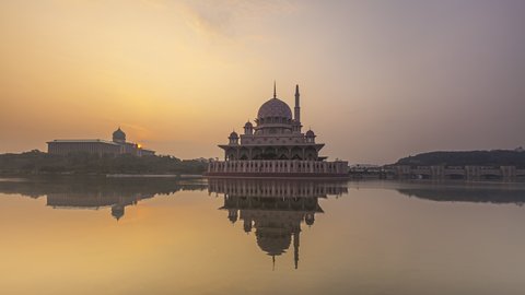 Beautiful Cloudy sunrise Time Lapse at Putra mosque by a lake in Putrajaya, Malaysia at dawn. Pan up motion timelapse. Prores 4KUHD