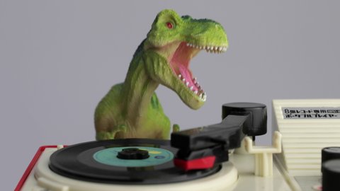 Footage of plastic toy tyrannosaurus rex dinosaur playing records on decks, dj dinosaur, djing, music, nightclub