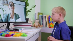 online education, boy with down syndrome show cards during learning school homework to a female teacher from home at the table with a computer
