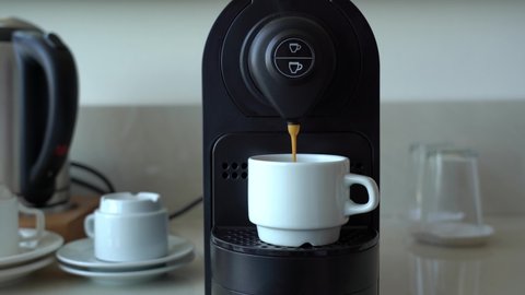 Man makes his morning cup of espresso coffee using small coffee machine