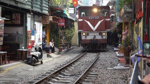 Hanoi, Vietnam - march 08, 2020 :  Train passing through a narrow street of the Hanoi Old Quarter, Vietnam. The Hanoi Train Street is a popular tourist attraction.