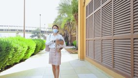 Asian woman carrying a shopping bag with groceries while wearing mask and gloves to prevent coronavirus Covid-19 spread during the pandemic