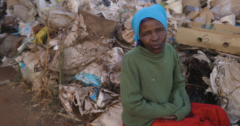 Face of poverty.  Inequality.Poverty.Close-up portrait panning view of a Poor Black African woman sitting next to a pile of rubbish in an informal settlement squatter camp slum. South Africa | Shutterstock HD Video #1059378986