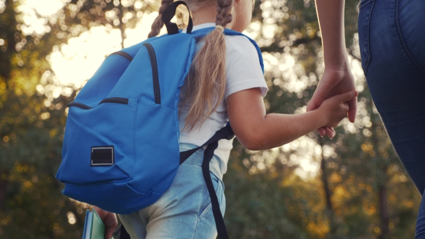 mom and daughter go to school. happy family education concept. schoolgirl with mom and daughter go hand in hand to school on footpath in lifestyle the park. little girl with a briefcase time to study Royalty-Free Stock Footage #1059384887