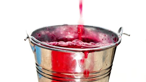 The red liquid is poured into a steel bucket and drip down, isolated on white background, slow motion.