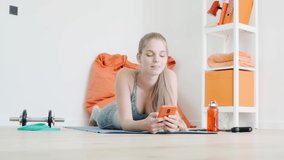 beautiful young woman in sportswear using cellphone at home