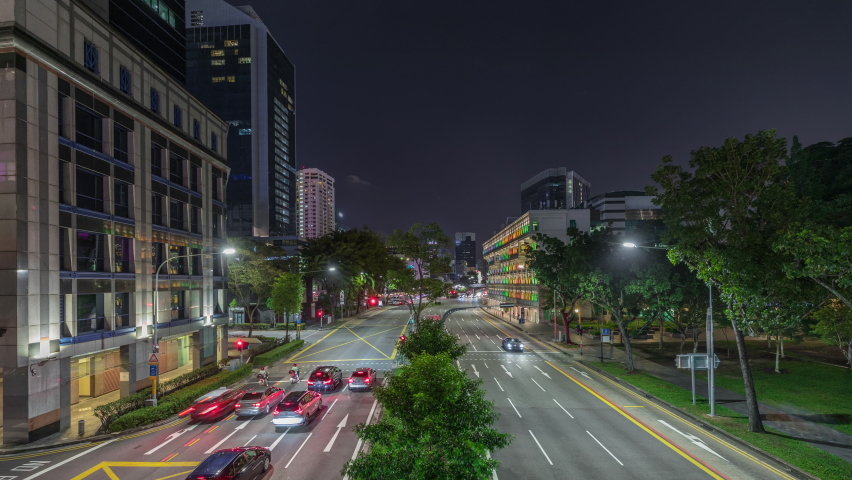 Road traffic with illuminated Old Hill Street Police Station historic building in Singapore night aerial timelapse. Neoclassical style building with colorful windows. Skyscrapers on a background
