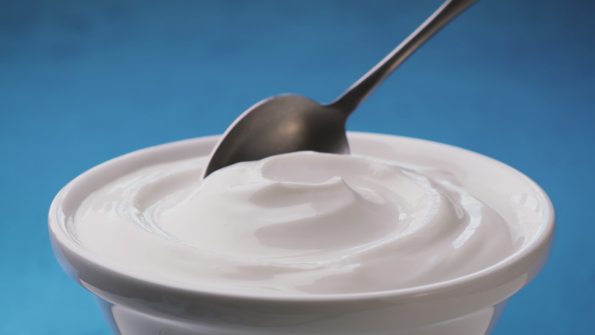 Bowl of sour cream on blue background, greek yogurt with spoon | Shutterstock HD Video #1059391901