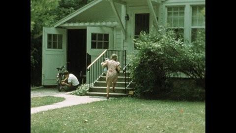 1950s: Two kids walk down sidewalk together, talking. Girl plays on yard with dolls while boy fixes bicycle. Two boys walk down road, talking.