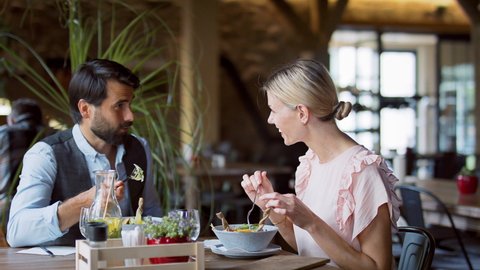 Couple sitting indoors in restaurant, talking when having lunch.