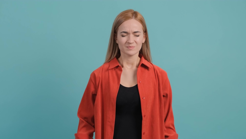 Headache. Close up of a young woman that feeling pain, holding her head with hand, suffering from bad head ache isolated over turquoise background.