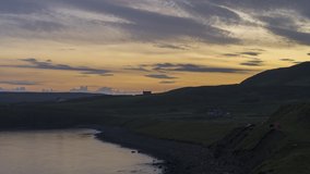Night to day transition of rocky coastline in Scotland, Isle of Skye. Sun rising, sheep grazing on pasture and wild camping in a red tent in countryside. 4k time lapse video