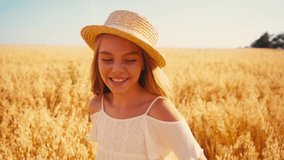 girl in white dress and straw hat showing thumb up in wheat field