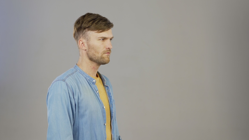 Waist up three quarter angle studio shot of mad fan cheering for somebody gesturing emotionally and celebrating success with yes gesture standing against grey background, copy space to right