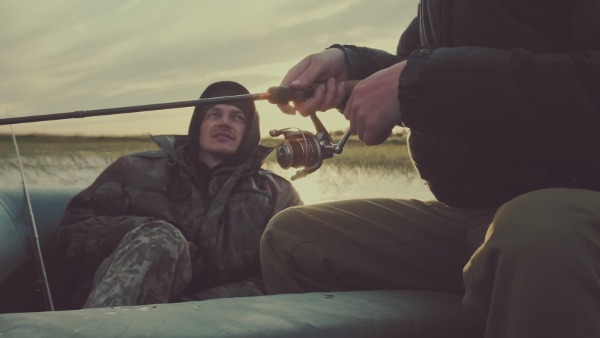 Friends fishing. Two friends fishing from the boat on the calm lake during sunset