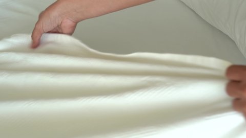 Closeup view of female hands making bed in bedroom