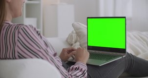 cheerful woman is using video call on laptop to communicate with friend, green screen on notebook for chroma key technology