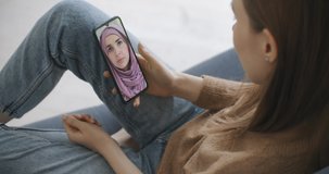 Female using medical app on smartphone consulting with Arab Muslim woman in hijab doctor via video conference. Female using online chat to talk with family therapist and pandemic of coronavirus.