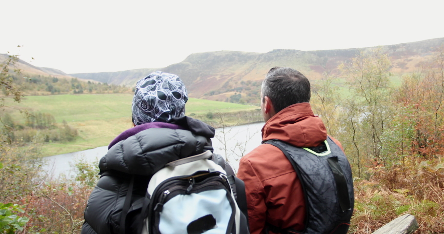 Rear view of two hikers sitting on bench in landscape / Yorkshire Moors, Yorkshire, UK