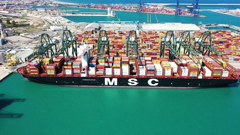 VALENCIA, SPAIN – AUGUST 25, 2020. Aerial view of the container ship MSC CRISTINA docked and downloading the containers by means of gantry crane in the port of Valencia.