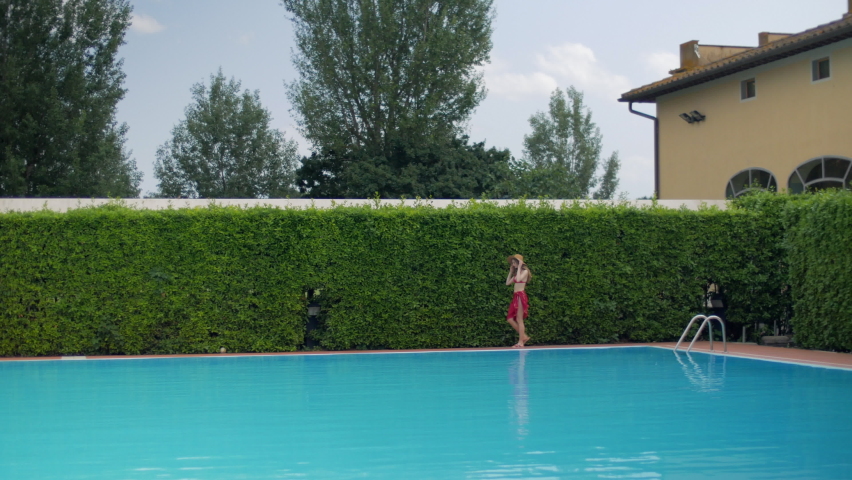 Young woman in bikini walking on poolside / Prato, Florence, Italy