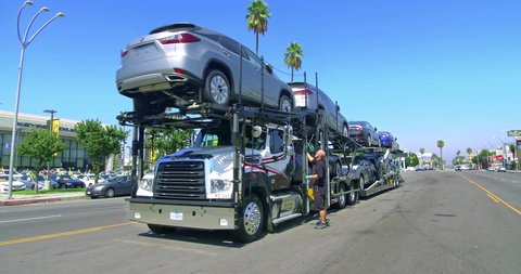 LOS ANGELES, CALIFORNIA, USA - SEPTEMBER 21, 2020: Car trailer carrier transporter arrived to Lexus auto dealership in Los Angeles, California, 4K