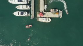 Drone video parallel to the marina with yachts and boats in the Adriatic Sea, waves and coastline and and landscape. Aerial shot Budva Montenegro.