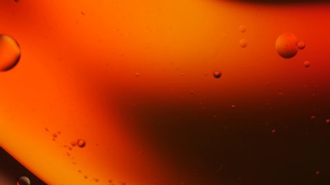 Dark gold color of oil drop floating on the water. Orange background of oil drop.