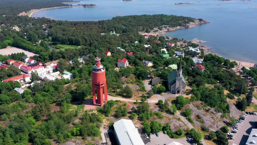 Aerial view around the Watertower and the church, revealing the cityscape and the sea, on a sunny, summer day, in Hanko city, Uusimaa, Finland - high, orbit, drone shot