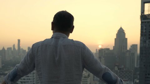 Young man admire beautiful sunset over city at luxury bar