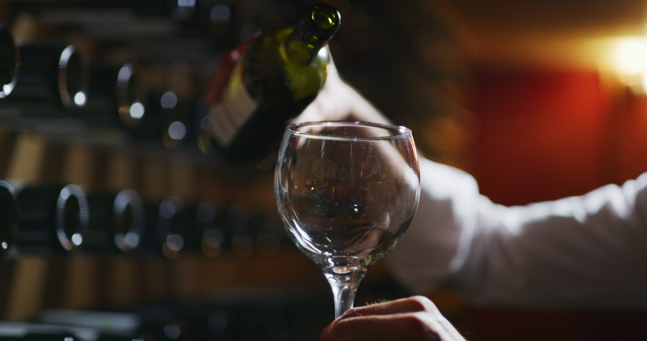 Close up shot winemaker or sommelier is pouring red wine in transparent glass for tasting a flavor and checking a quality  in a wine cellar. Royalty-Free Stock Footage #1059448457