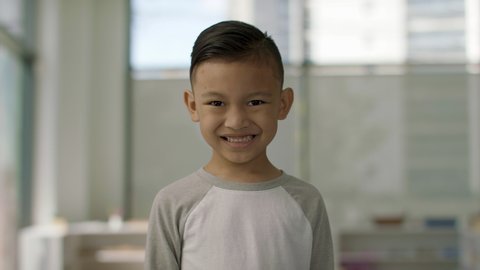 All smiles. Happy asian boy excited to be in the classroom. School is on and his friends are back. Shot in 4k. 
