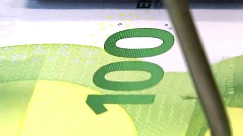 An extreme close-up of one hundred euro banknotes rolling off the printing press at speed - seamless looping.