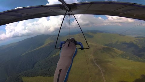 Hang glider pilot races high in the mountains. On board video of extreme sport.