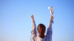 Girl run and raise her hands with a golden cup over her head and celebrate her victory. Action in real time. The happiness of victory. Highest award - Powered by Shutterstock - Get 15% off with code: PIKWIZARD15