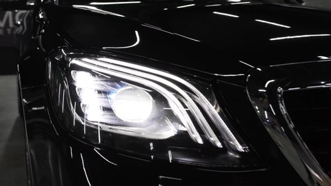 Close up of details of headlights of anonymous prestigious black luxury modern car. Concept of passion for driving cars, car dealerships,luxury cars. Shot in 4K.